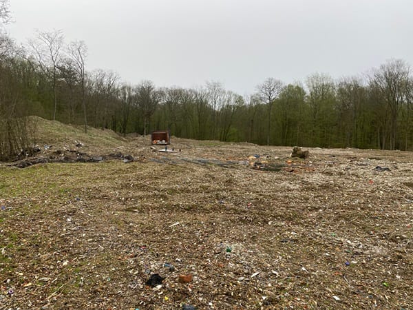 Photo showing a landfill of rubbish with trees around the outside.