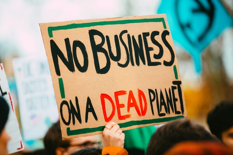 A protest placard reading 'No business on a dead planet'